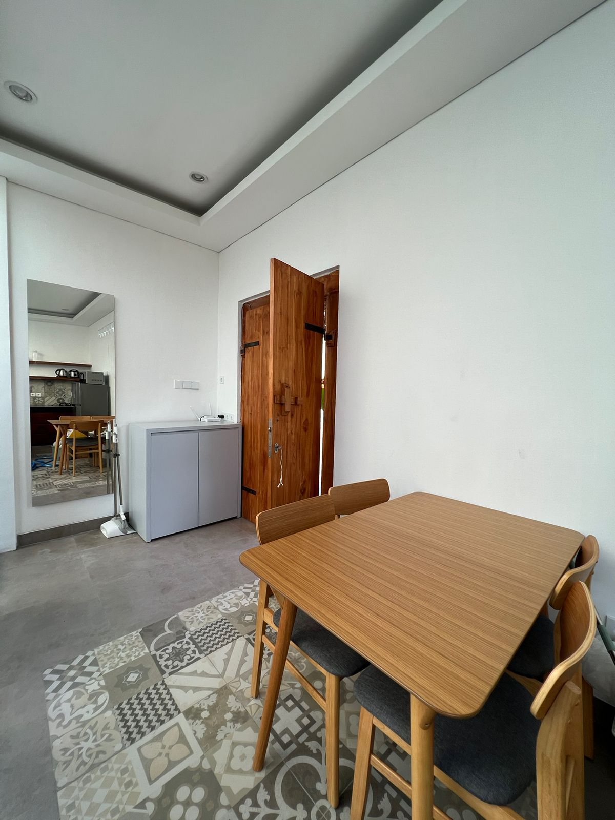 A modern interior with a dining table and chairs, a kitchen area, and a wooden door.