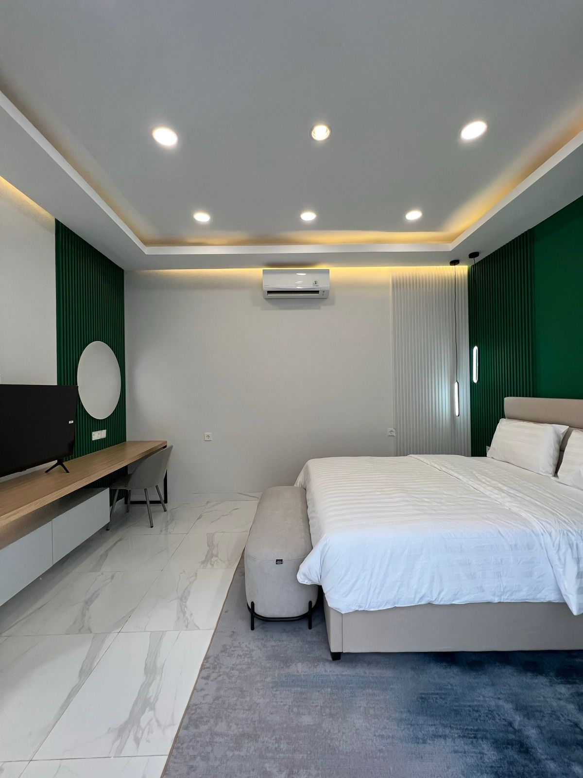 A modern bedroom with a bed, bedside table, chair, and a TV.