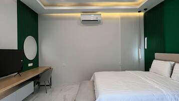 A modern bedroom with a bed, bedside table, chair, and a TV.