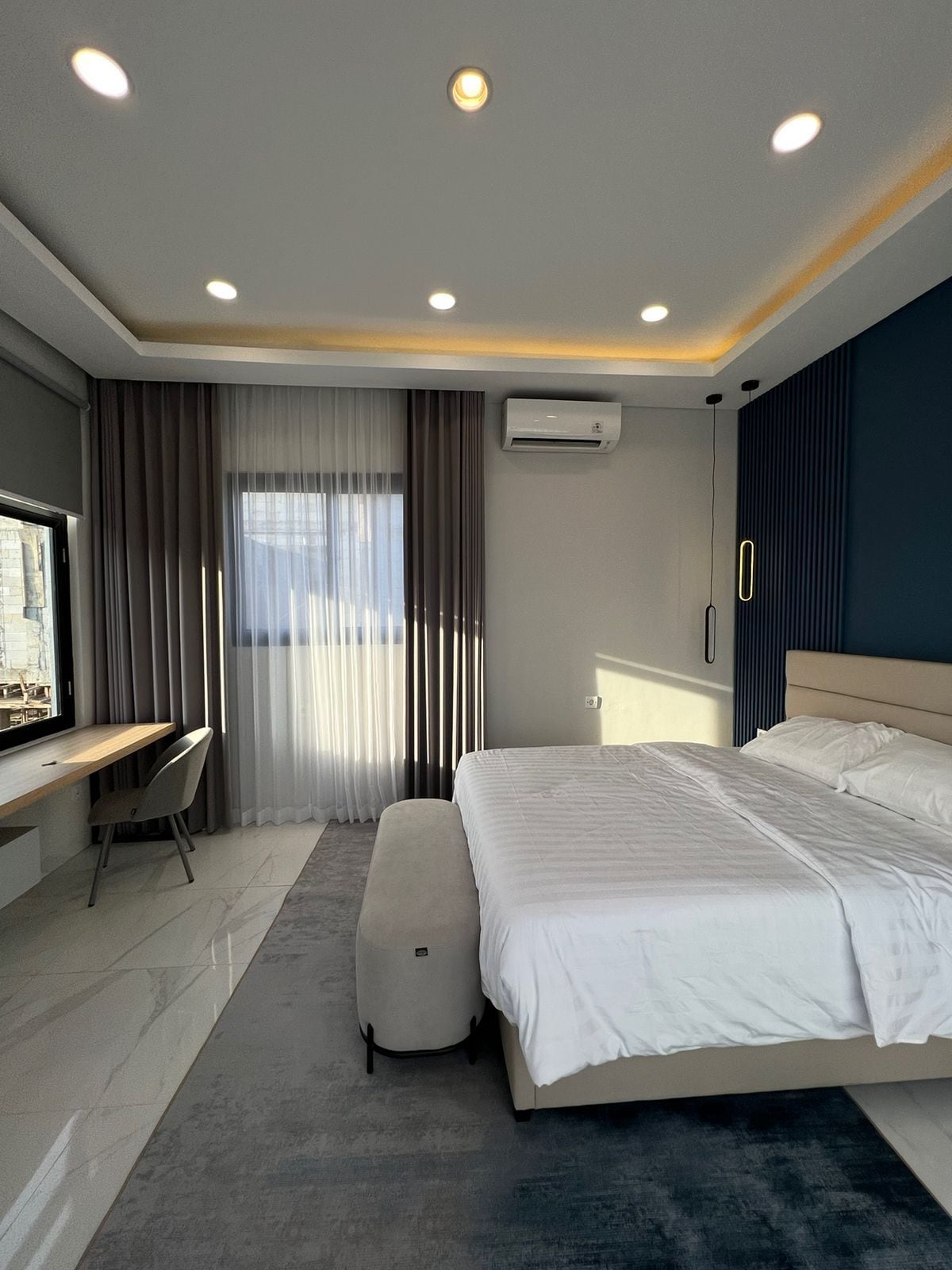 A modern hotel room with a bed, a desk, and a chair.