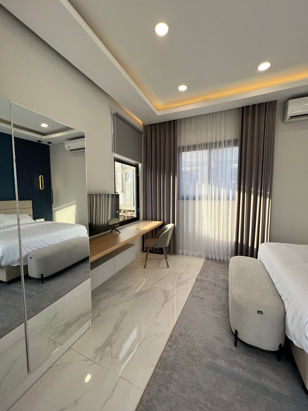 Una camera d'albergo moderna con un letto, una scrivania, una sedia e uno specchio grande.