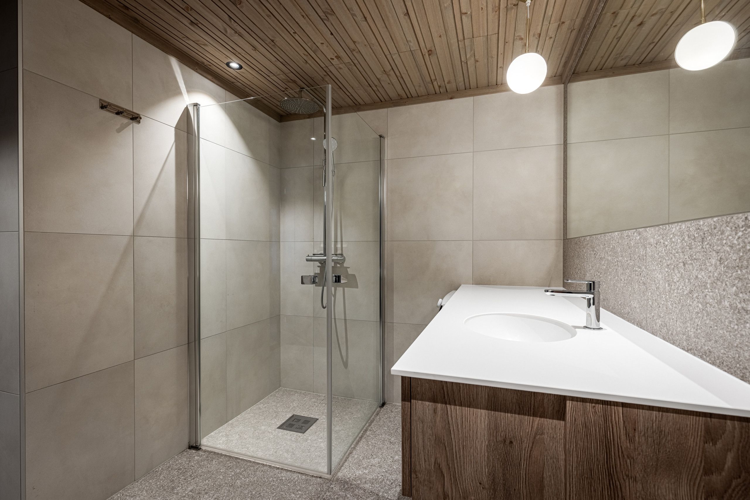 Une salle de bain moderne avec une douche à parois de verre, un meuble-lavabo en bois et un lavabo blanc.