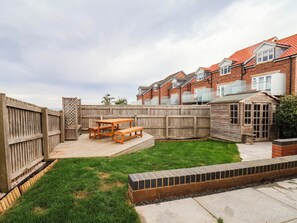A backyard with a wooden deck, a picnic table, and a brick planter. - Eyrie Heights (Whitby)