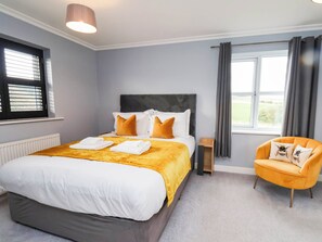 A hotel room with a bed, a chair, a window, and a radiator. - Eyrie Heights (Whitby)