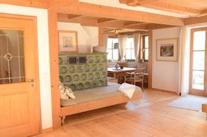 A room with a wooden bench, a table, chairs, a window with curtains, and a painting on the wall. - Bergundmoos, Allgäu - A Vacation Home for the Whole Family (Pfronten)