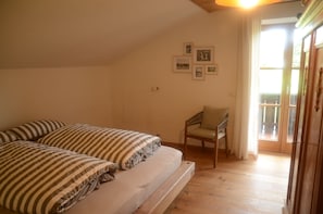 A bedroom with a bed, a chair, and a balcony. - Bergundmoos, Allgäu - A Vacation Home for the Whole Family (Pfronten)
