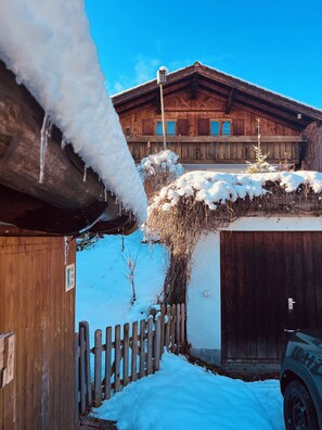 A wooden building with a snow-covered roof and a wooden fence in front. - Bergundmoos, Allgäu - A Vacation Home for the Whole Family (Pfronten)