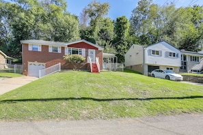 A residential area with houses, a white car, and a grassy lawn.