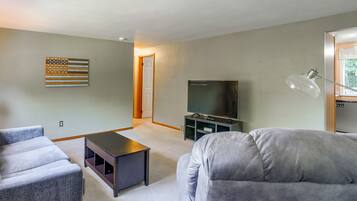 Een woonkamer met een flatscreen televisie, een bijzettafeltje en een bank.