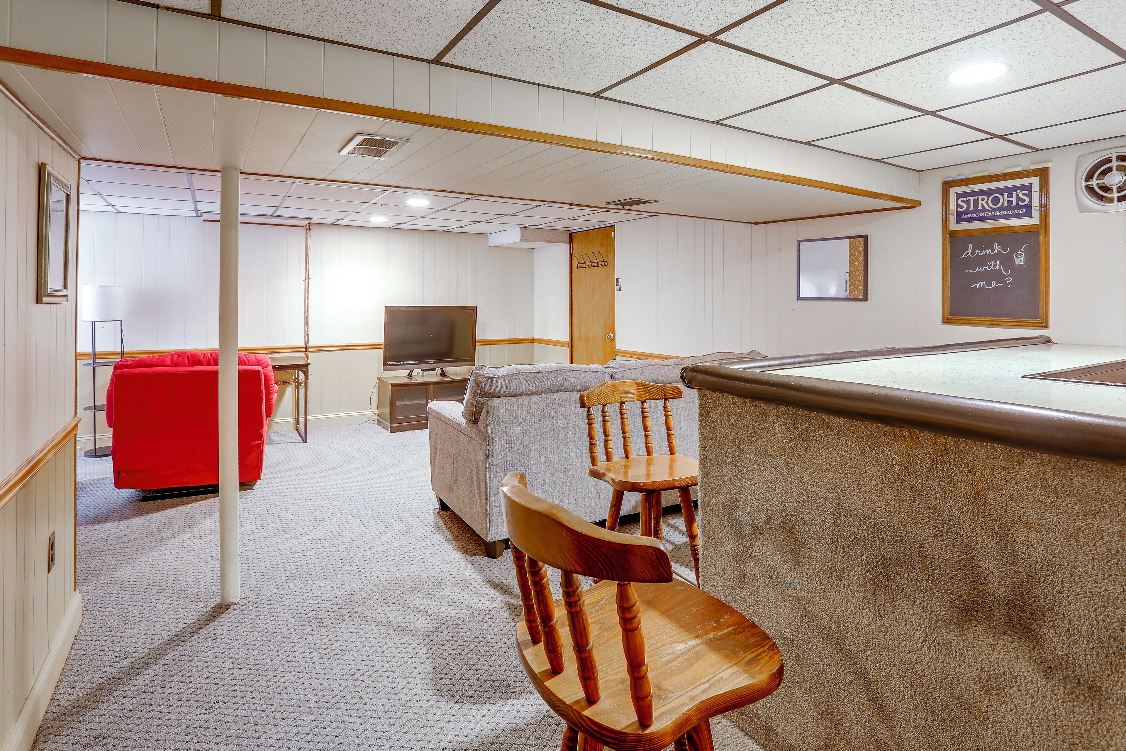 A room with a pool table, a red chair, a television, and a wall with a sign.