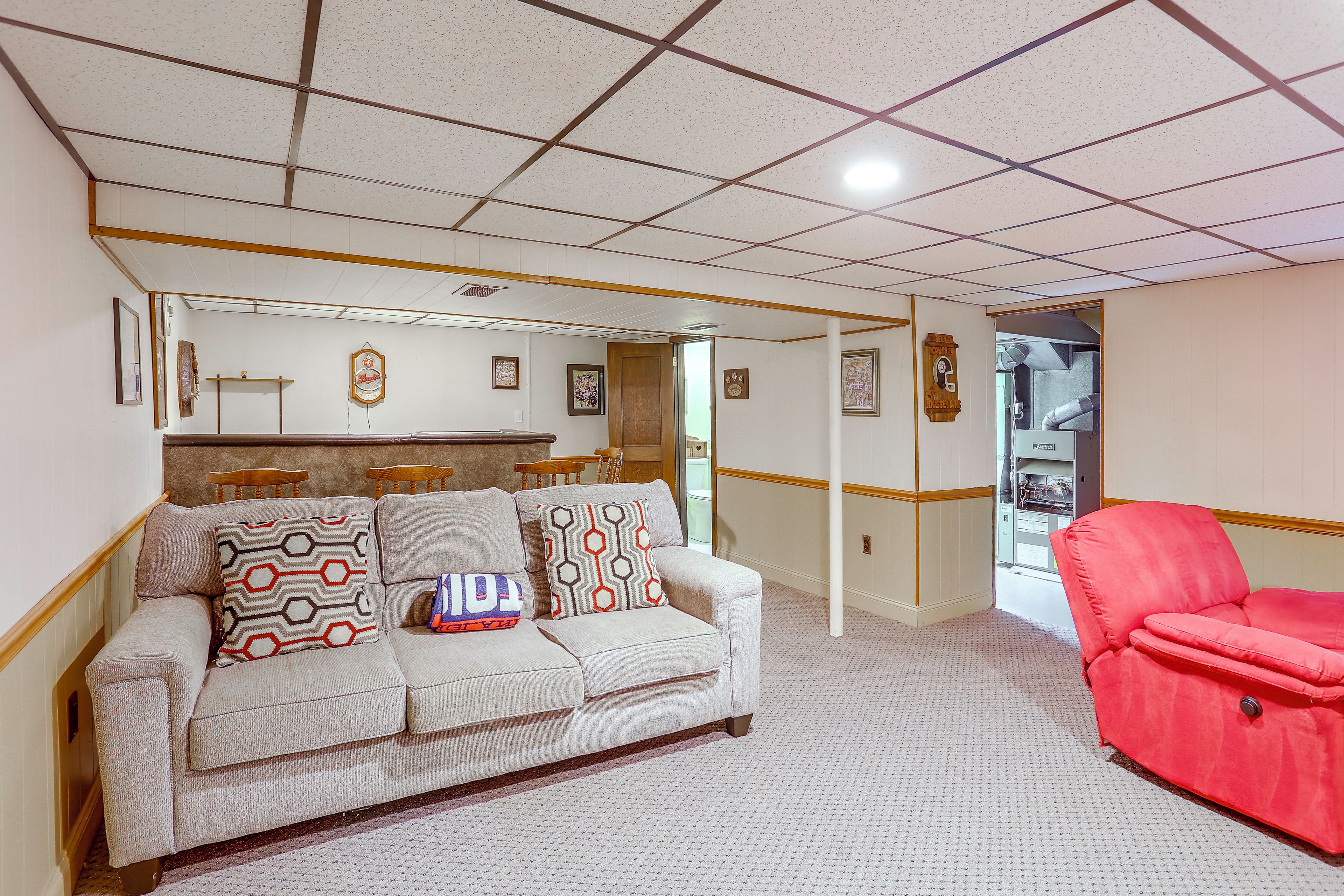 A living room with a beige sofa, a red armchair, and a patterned throw pillow.