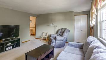 A living room with a television, a sofa, a chair, and a small table.