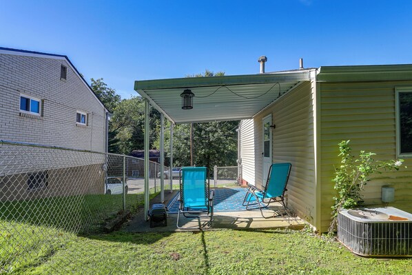 A covered patio area with a pool, two chairs, and a water feature.