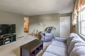 A living room with a television, a sofa, a recliner, and a small table.