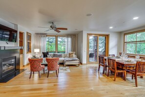 A spacious living area with a fireplace, seating, and a dining table. - Sun Valley Extended Stay: Central Condo w/ Patio (Ketchum)