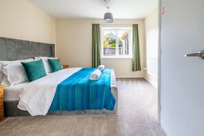 Ein Hotelzimmer mit einem Bett, einem Nachttisch, einem Fenster mit Vorhängen und einer Tür.