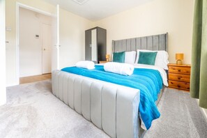 Ein Schlafzimmer mit Bett, Nachttisch, Kleiderschrank und Teppichboden.