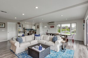 Ein modernes Wohnzimmer mit einer Eckcouch, einem Couchtisch und einem Essbereich mit einem Holztisch und Stühlen.