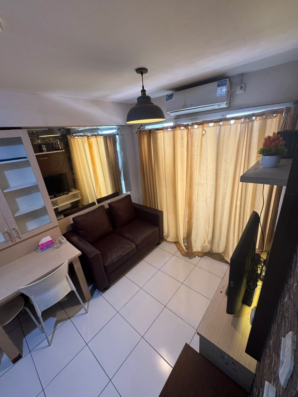 Un soggiorno con divano, televisore, tavolo e ventilatore a soffitto.