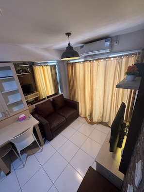 Un salon avec un canapé, un téléviseur, une table et un ventilateur de plafond.