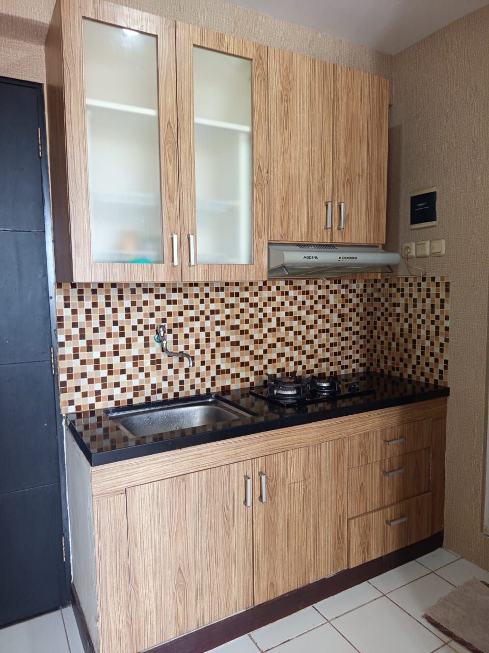 Una cucina con mobili in legno, una parete di fondo rivestita di piastrelle e un fornello a gas.