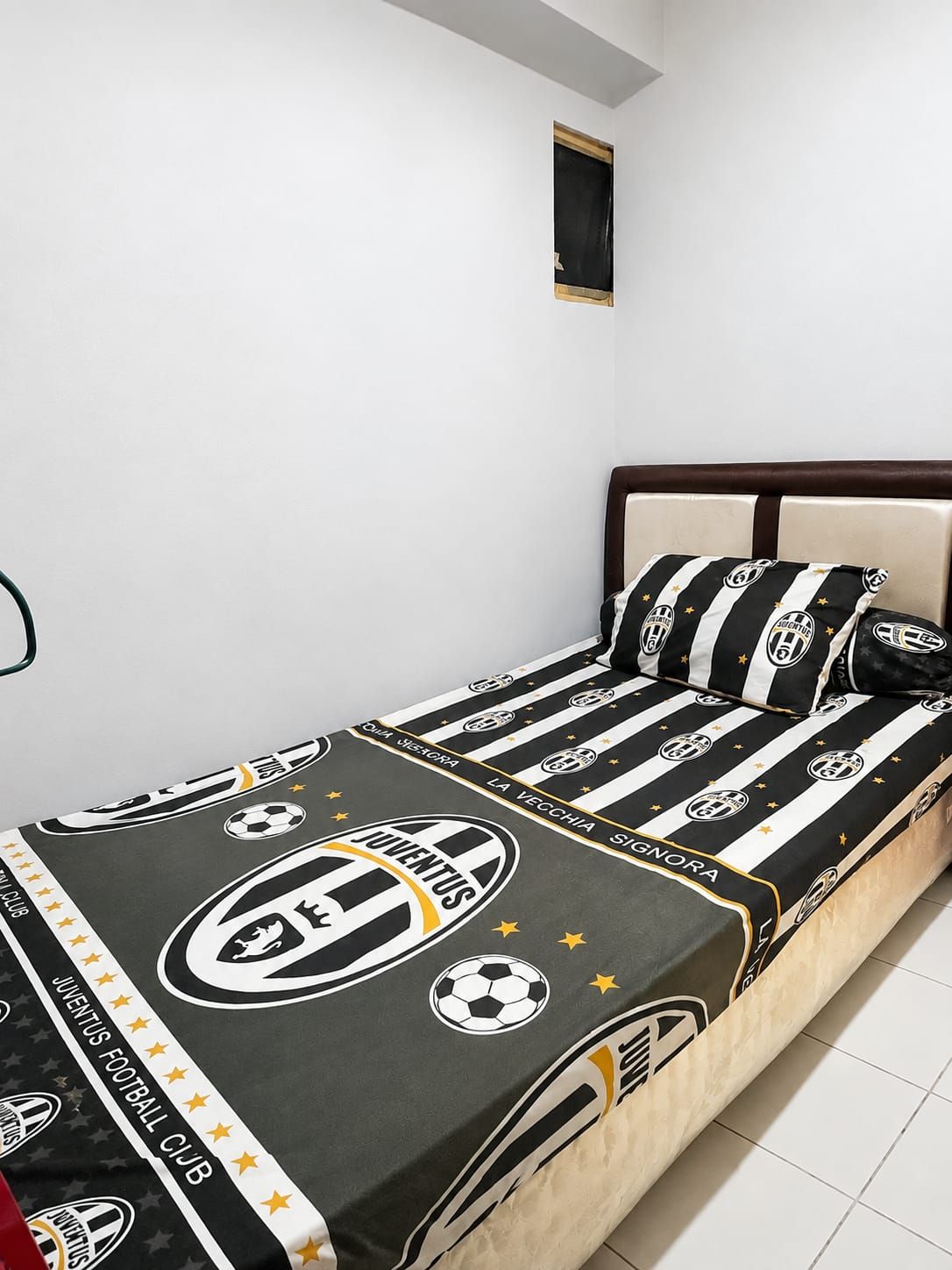 A bed with a black and white striped bedding featuring a football club logo.