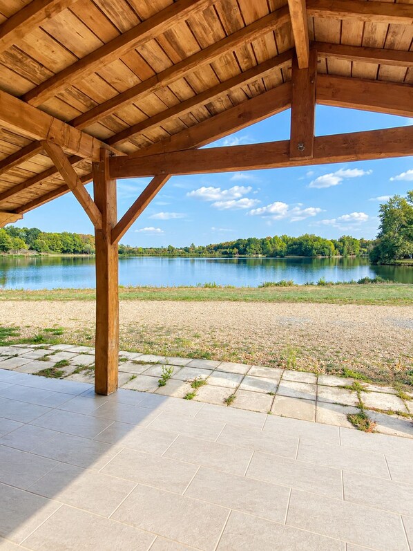 A covered outdoor area with a view of a lake and trees.