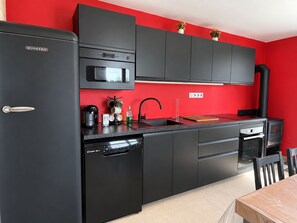 Eine moderne Küche mit schwarzen Geräten, einer roten Akzentwand und einer schwarzen Arbeitsplatte.
