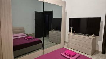 Ein Schlafzimmer mit einem Bett, einer Kommode, einem Spiegel und einem Fernseher.