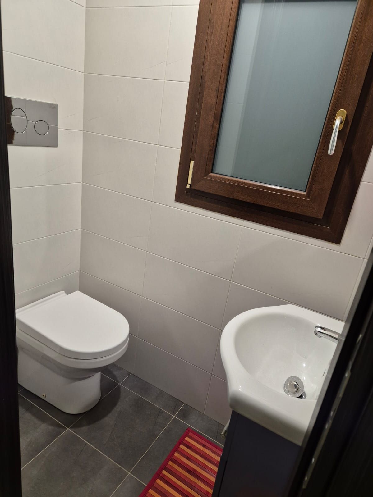 A small bathroom with a toilet, a sink, and a mirror.