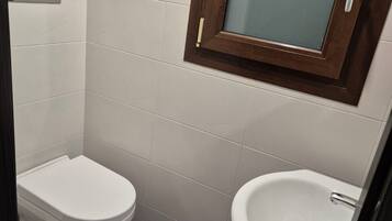 A small bathroom with a toilet, a sink, and a mirror.