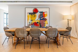 A dining area with a long wooden table, six wicker chairs, and a large abstract painting on the wall. - Cubo's Villa La Caldera / private pool / gym / vineyards / luxury experiences / free Wi-Fi (Ronda)