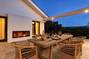 An outdoor dining area with a fireplace, wicker furniture, and a view of the hills. - Cubo's Villa La Caldera / private pool / gym / vineyards / luxury experiences / free Wi-Fi (Ronda)