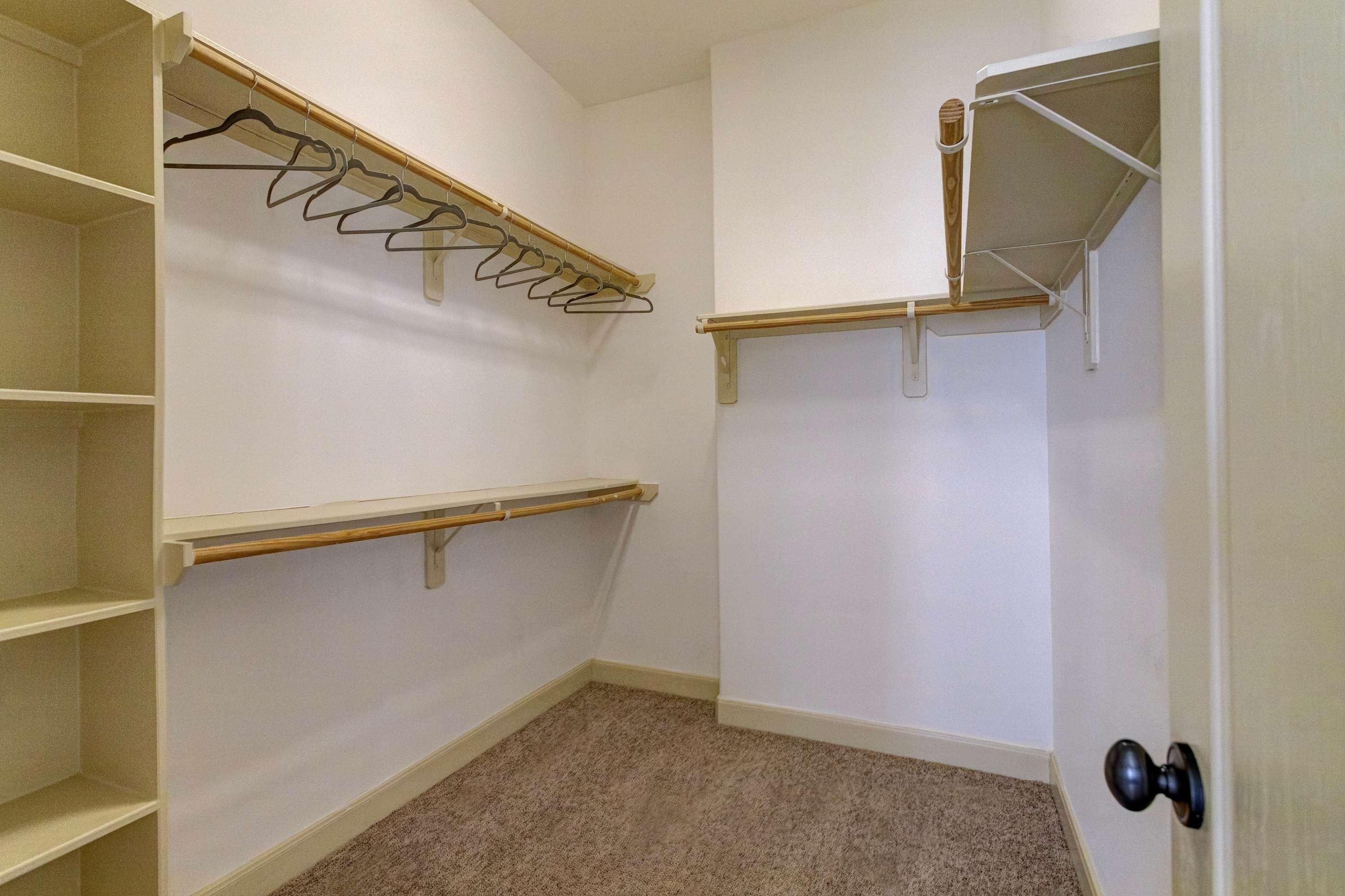 A walk-in closet with open shelving, a hanging rod, and a door with a doorknob.