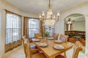 A dining room with a large wooden table set for six, surrounded by chairs, with a chandelier above. - Sleeps 16 Pool Slide Family Retreat (Porter)
