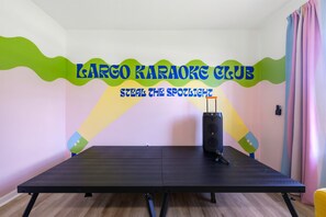 A room with a large black table, a karaoke machine, and a wall with colorful text. - Pool Hot Tub Putt Putt Game Room Karaoke (Largo)
