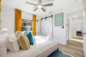 A bedroom with a bed, pillows, a ceiling fan, a window with curtains, a door, and a wall-mounted light. - Pool Hot Tub Putt Putt Game Room Karaoke (Largo)