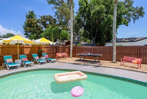 Un patio trasero con piscina, sillas de descanso, una mesa y un banco.