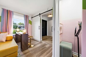 A modern living room with a sofa, a small table, and a chair. There is a sliding door leading to another room. - Pool Hot Tub Putt Putt Game Room Karaoke (Largo)