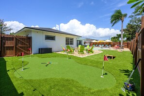 A backyard with a pool, green chairs, and a small house. - Pool Hot Tub Putt Putt Game Room Karaoke (Largo)