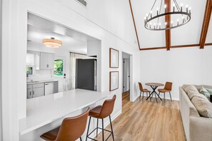 Eine moderne Küche mit einer großen Kochinsel, einem Essbereich mit Stühlen und einem Wohnzimmer mit einer Couch.