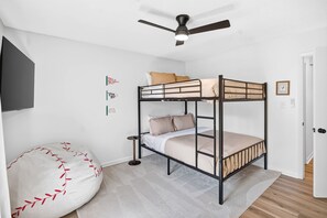 Ein Stockbett, ein Deckenventilator, ein Sitzsack und ein kleiner Tisch.