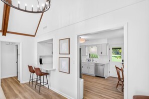 Una cocina moderna con armarios blancos, lavavajillas integrado y una ventana con vistas a zonas verdes.