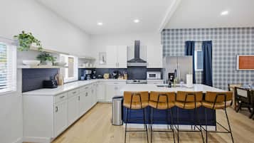 A modern kitchen with white cabinetry, a central island with bar stools, a microwave, and a gas stove.