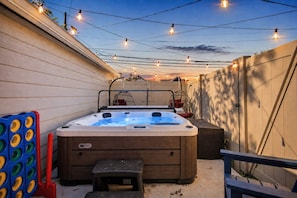 Een hottub met een houten buitenkant, een bankje en een kleine tafel in een achtertuin.