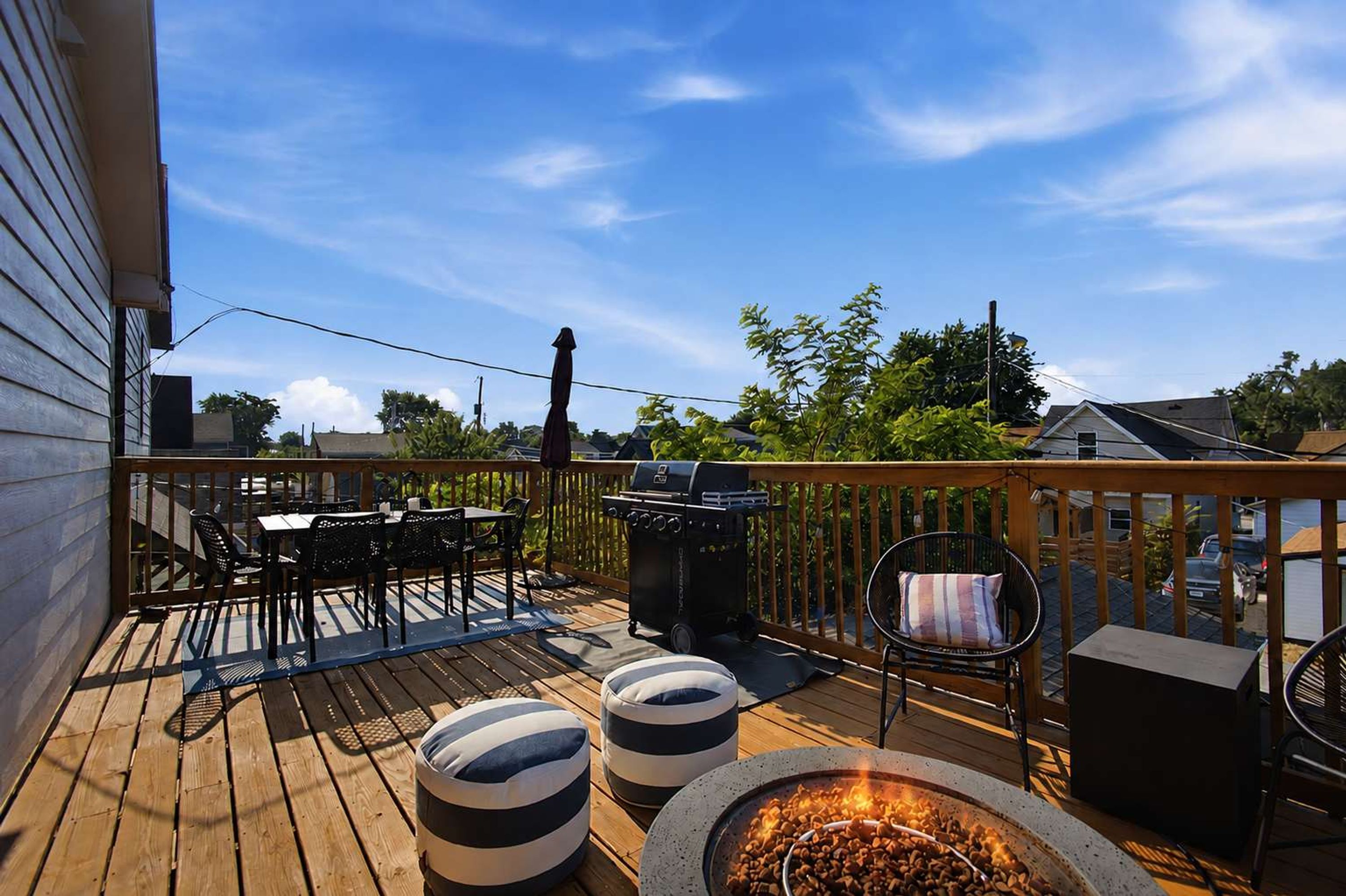 Une terrasse en bois avec des meubles d’extérieur, un barbecue et un foyer.