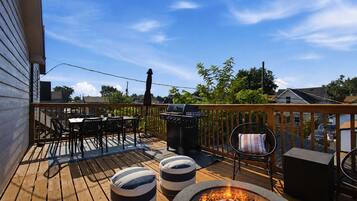 Une terrasse en bois avec des meubles d’extérieur, un barbecue et un foyer.