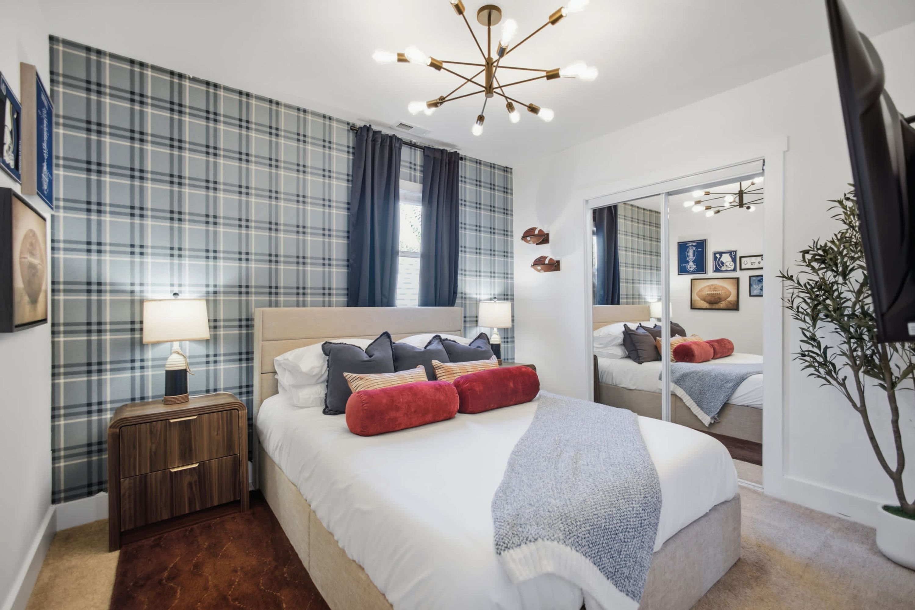 A modern bedroom with a large bed, a nightstand, a mirror, and a ceiling light fixture.