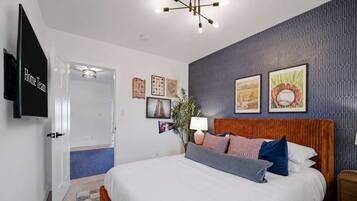 Une chambre d’hôtel avec un grand lit, un téléviseur à écran plat et un mur orné de souvenirs sportifs encadrés.