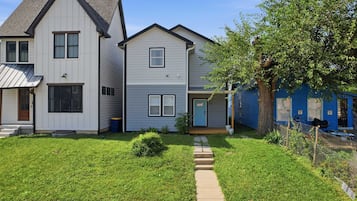 A residential area with a row of houses, a well-maintained lawn, and a clear sky.